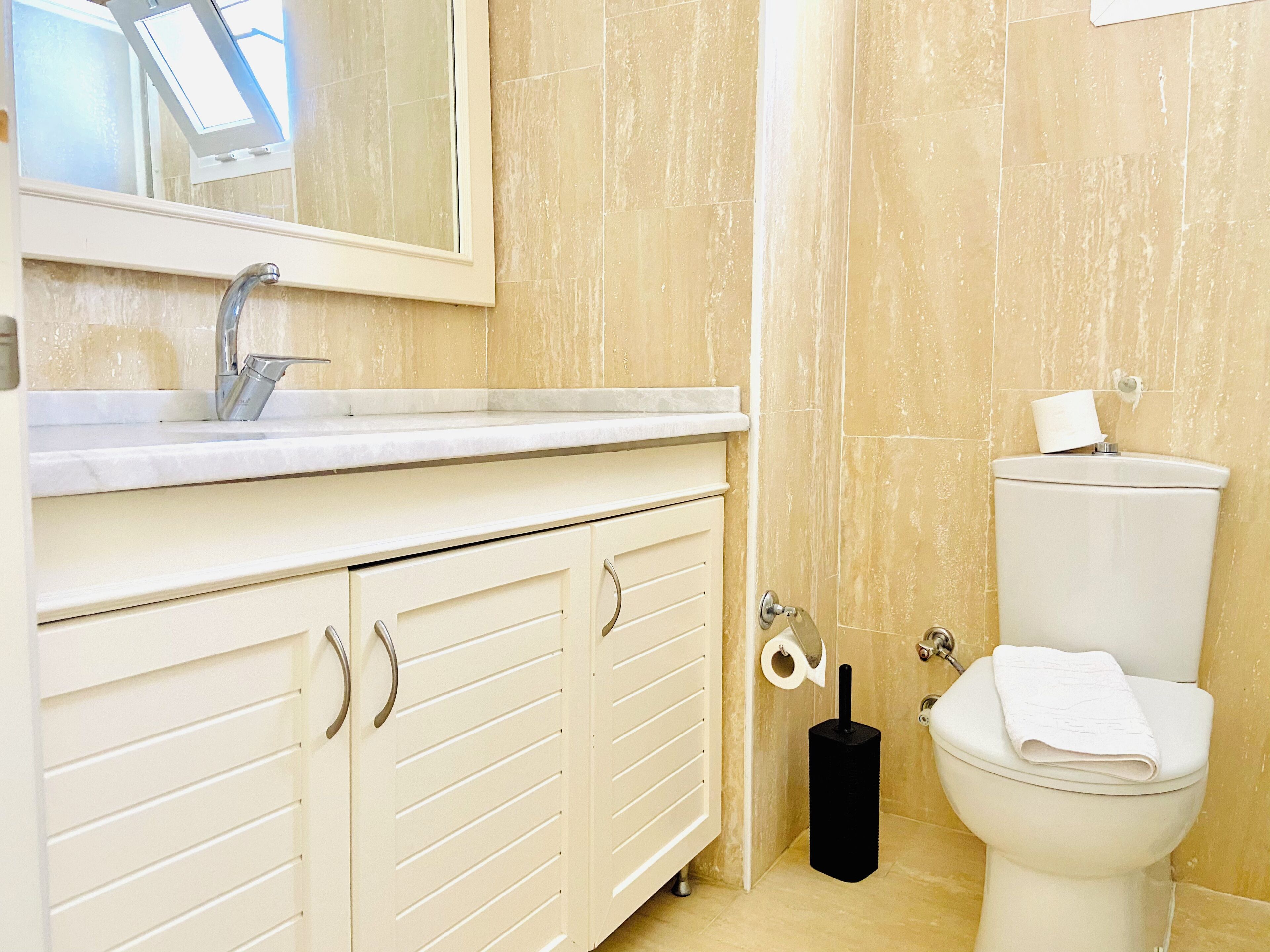 A bathroom with a white sink, mirror, and toilet.