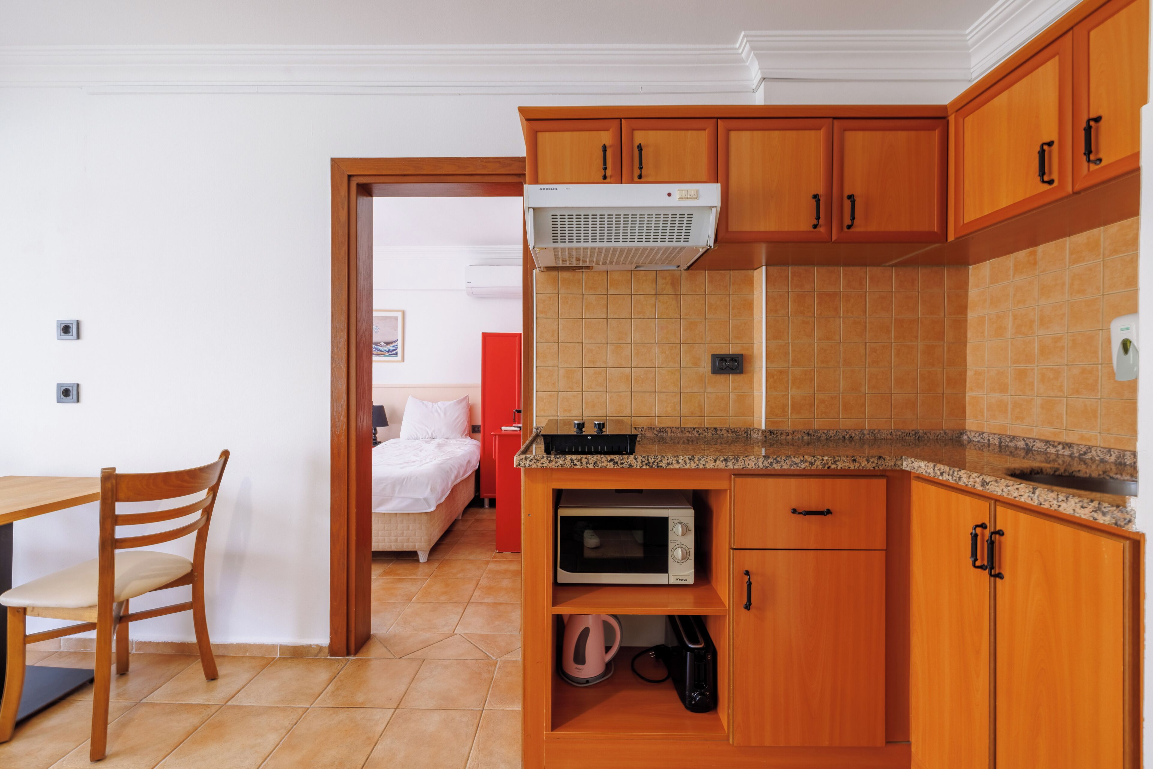 A compact kitchen with wooden cabinets, a microwave, and a coffee maker.