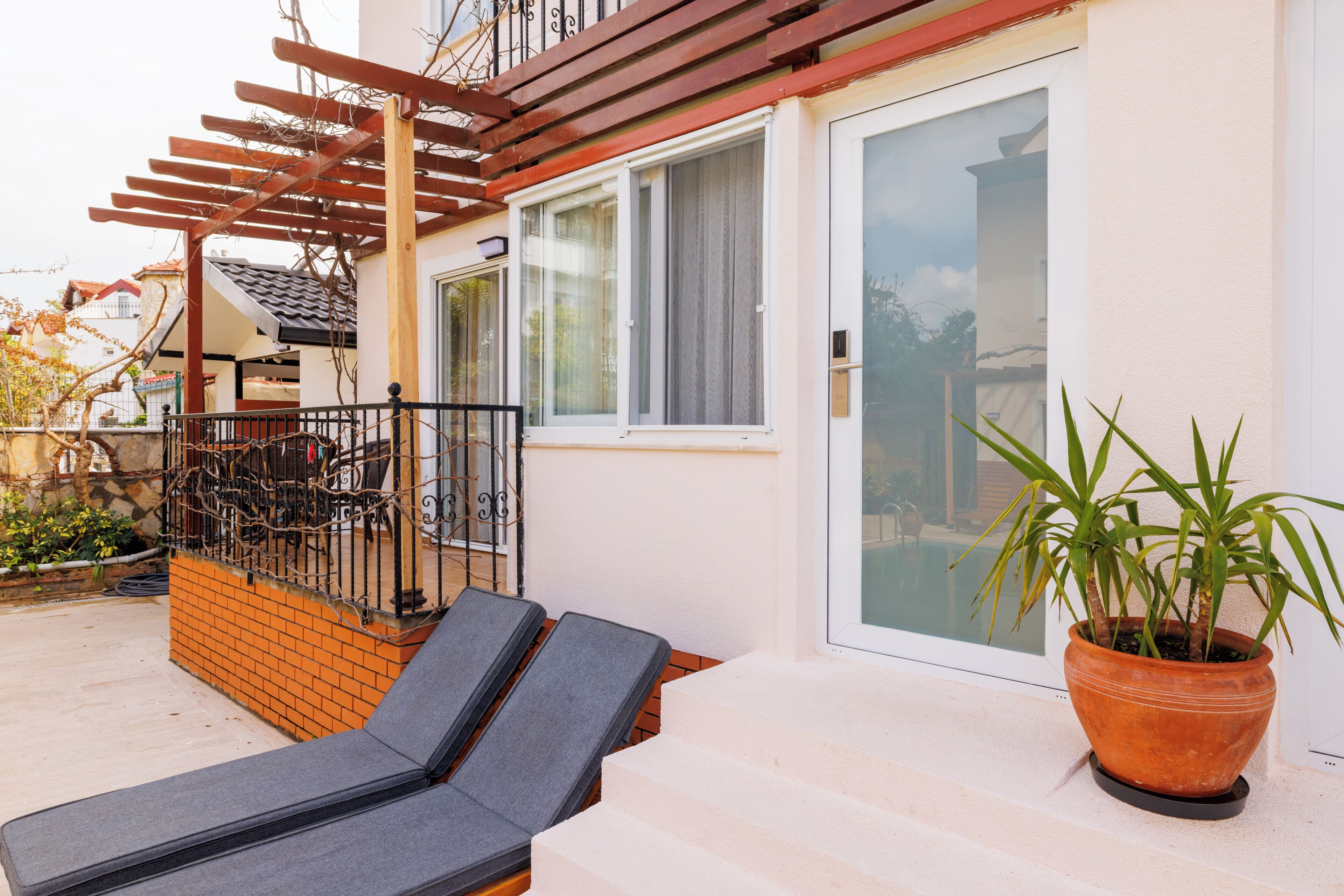 Ein Balkon mit einer Pergola, einem Blumentopf und zwei Liegestühlen.