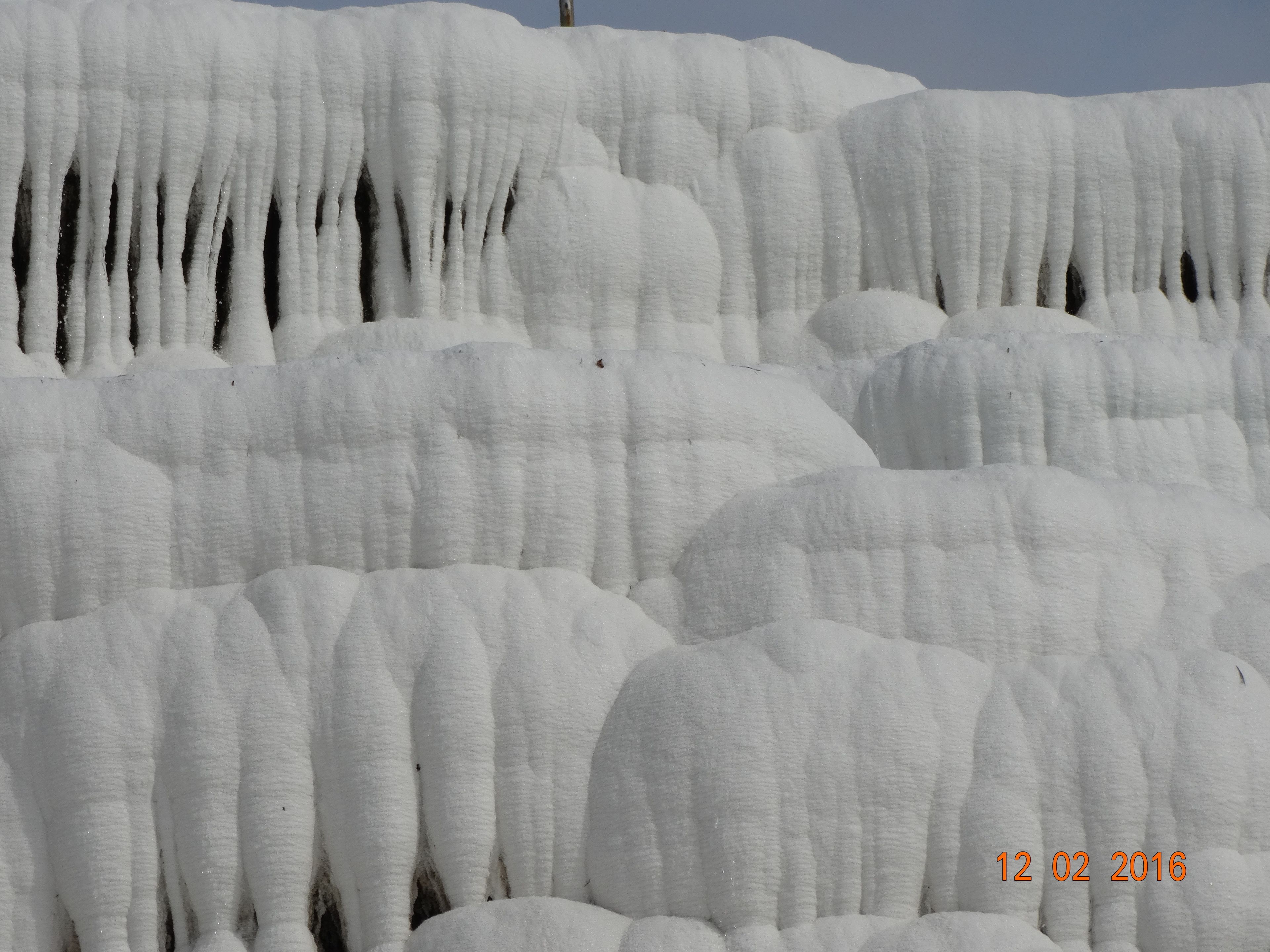 Primer plano de una formación rocosa cubierta de nieve con vetas verticales.