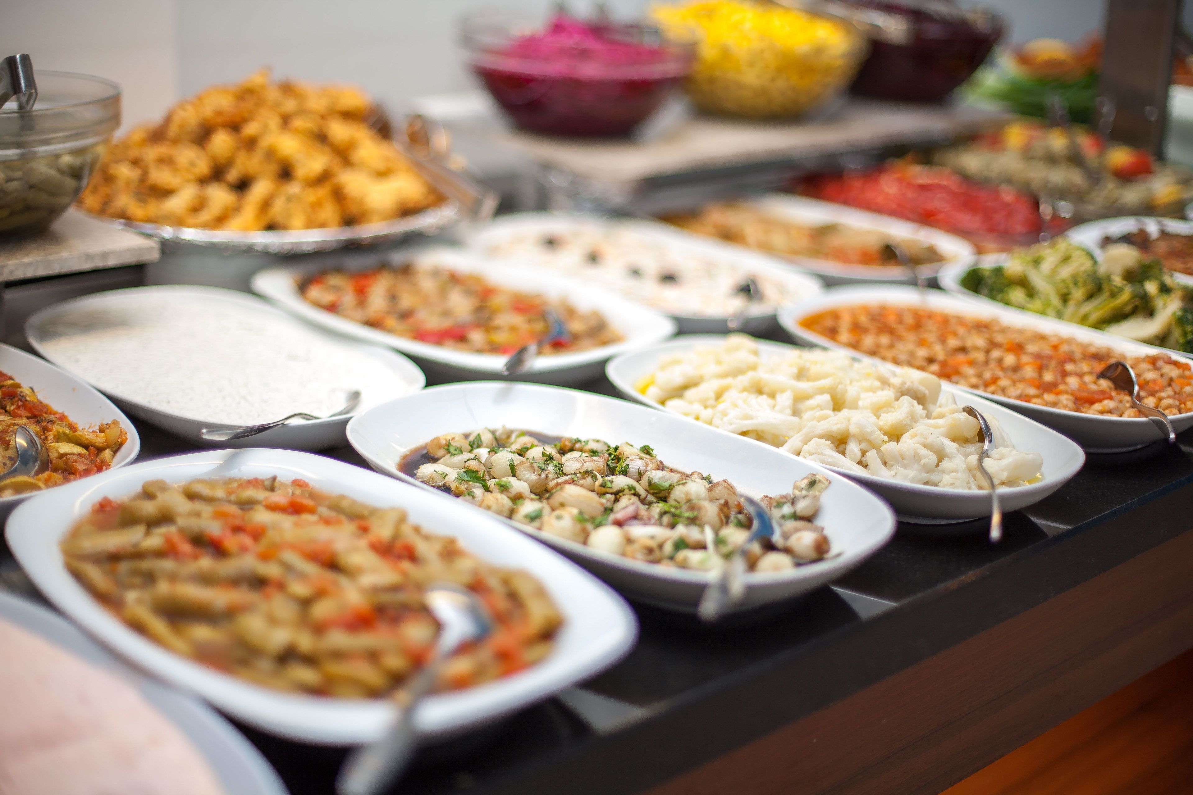 A buffet with various dishes including pasta, salads, and rice.