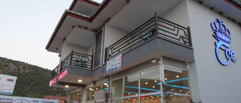 A hotel with a modern design, featuring a balcony, large windows, and a sign indicating it is a hotel.