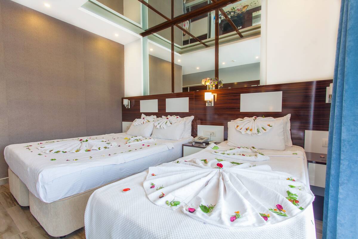 Een hotelkamer met twee bedden, elk versierd met bloemen en witte lakens.