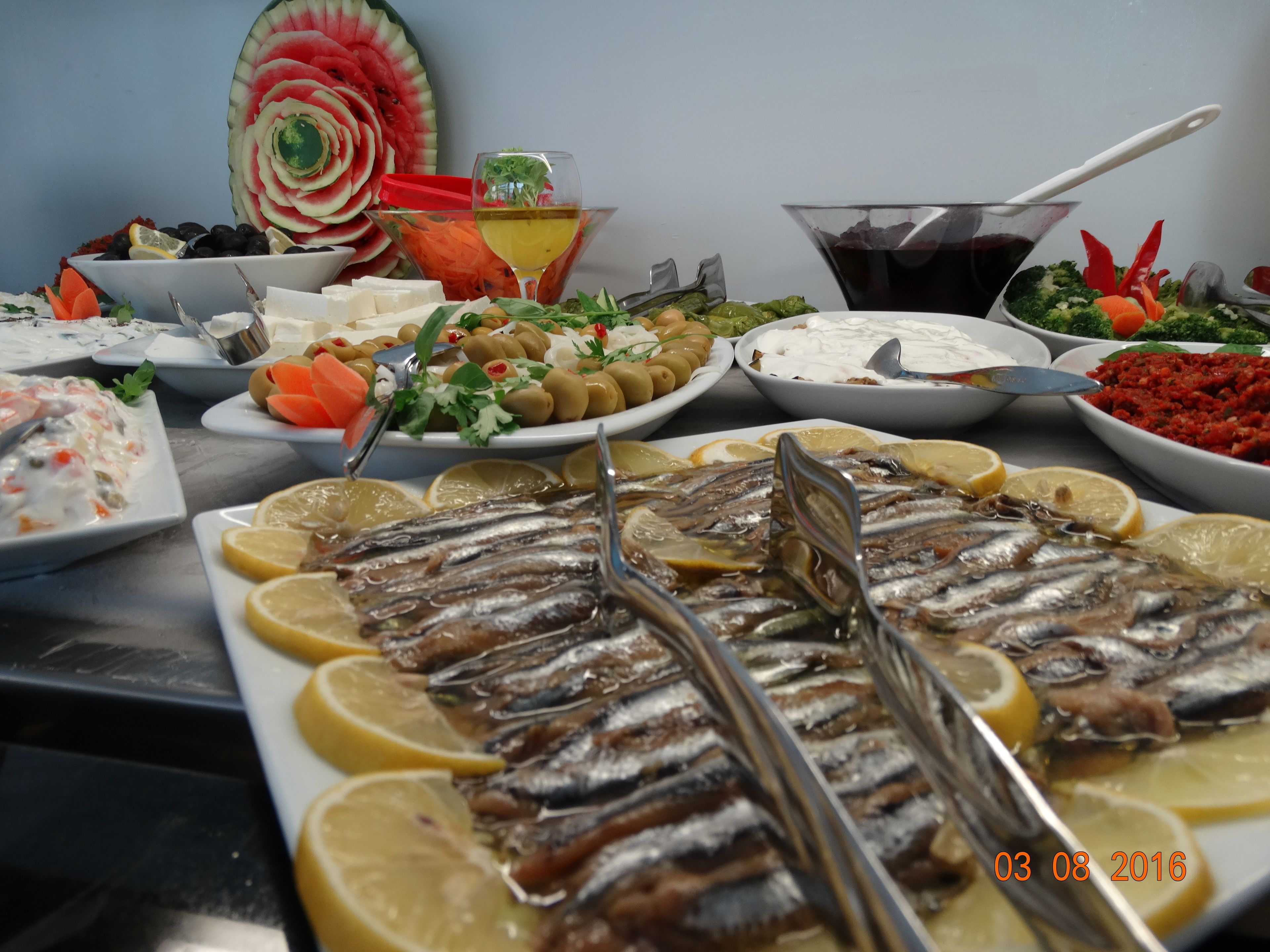 Un bufé con diversos platos, incluyendo pescado, aceitunas y ensaladas.