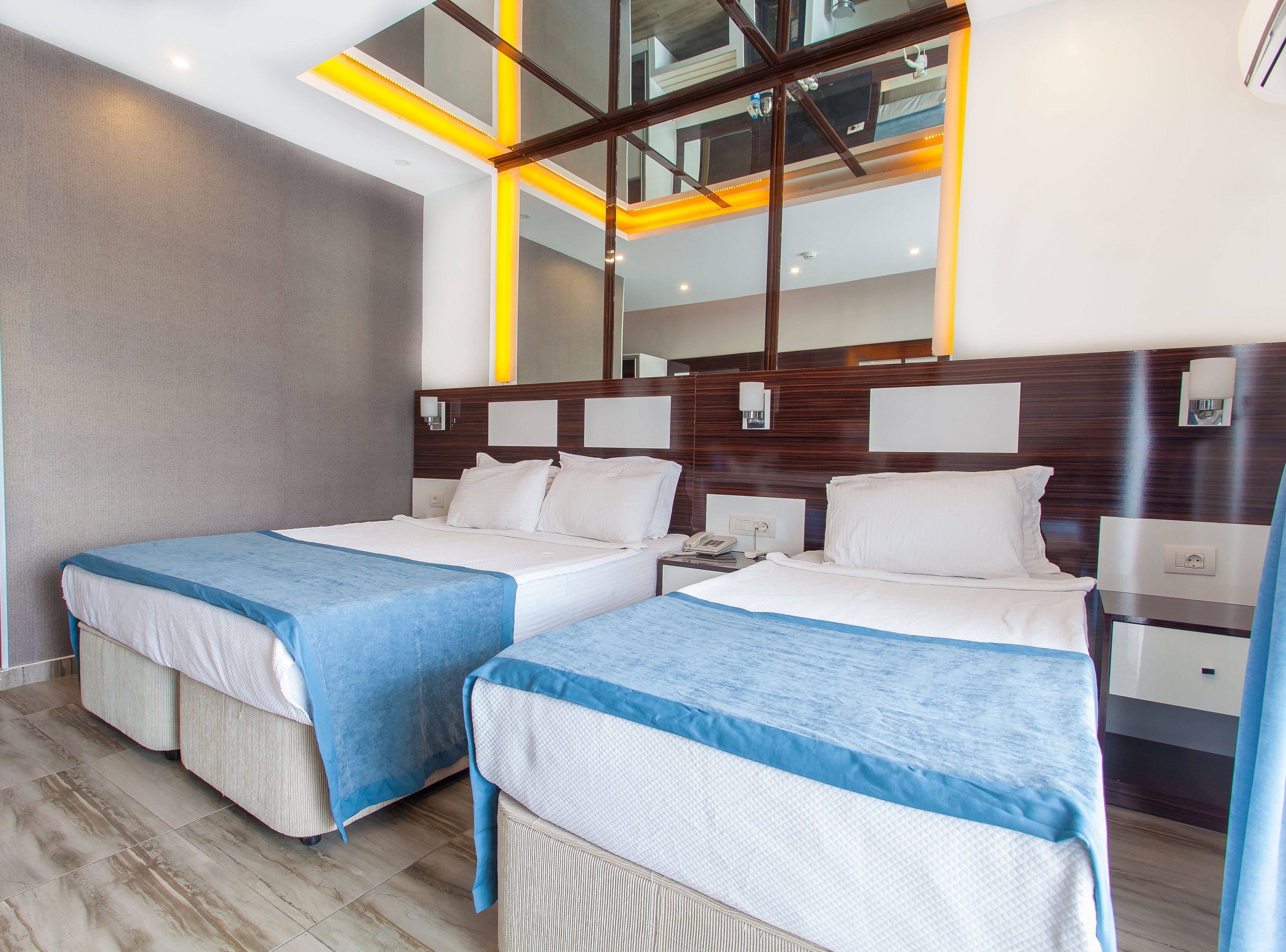 Una habitación de hotel con dos camas, un espejo grande y un diseño moderno.