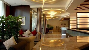 Un moderno vestíbulo de hotel con área de descanso, una recepción y una araña.