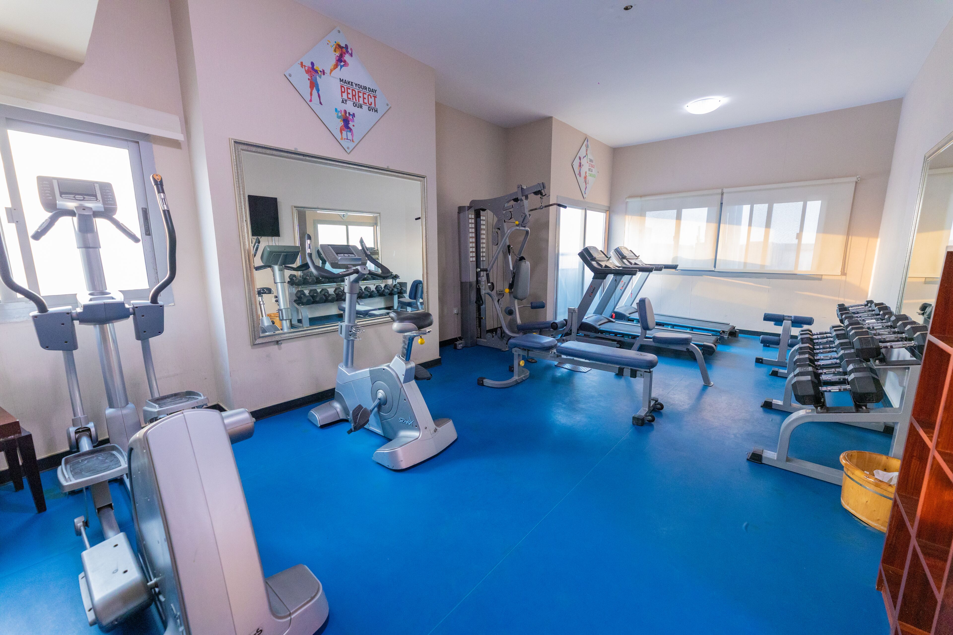 Une salle de sport équipée de tapis de course, de vélos elliptiques et de poids libres.
