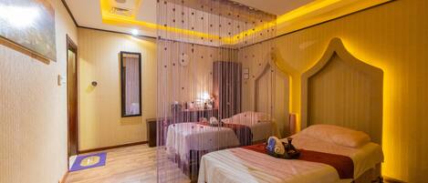 A hotel room with two beds, a large mirror, and a ceiling with yellow lighting.