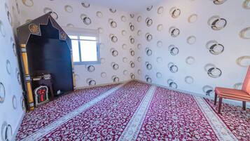 A room with a patterned carpet, a star-shaped door, a window, and a chair.