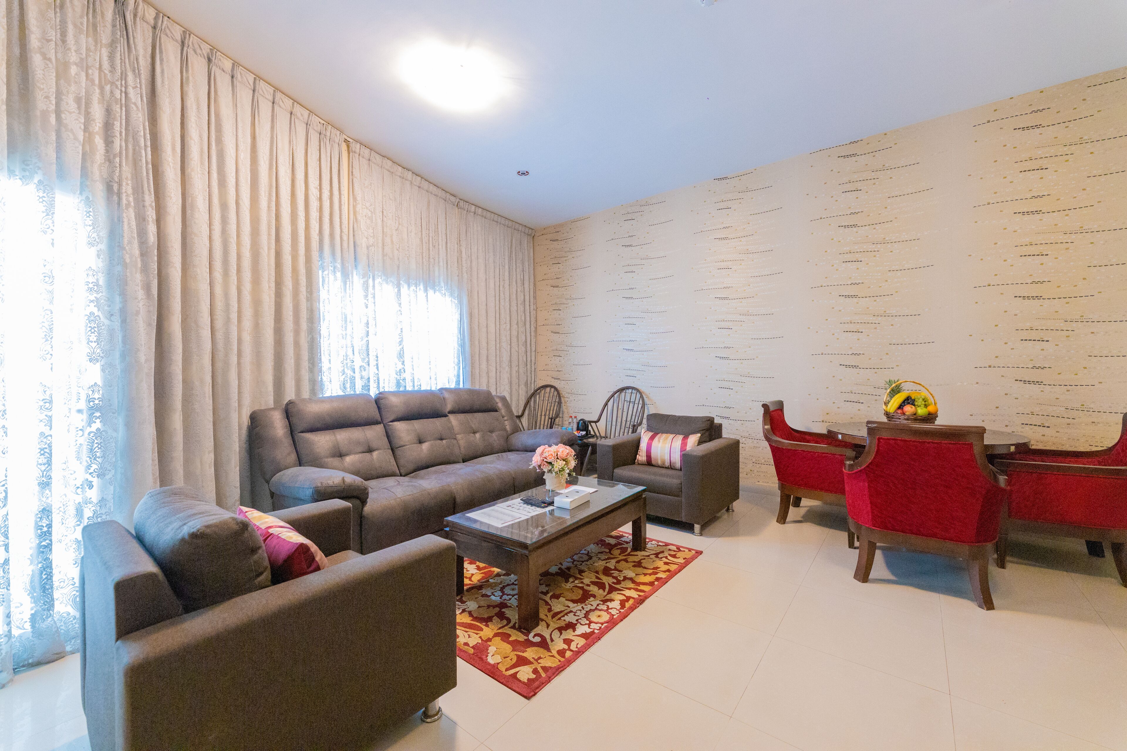 A living room with a sofa, armchairs, a coffee table, and a dining table with chairs.
