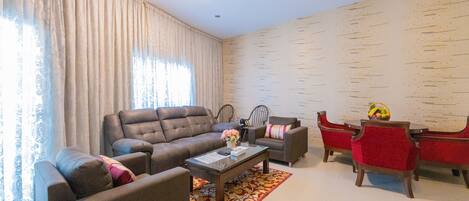 A living room with a sofa, armchairs, a coffee table, and a dining table with chairs.