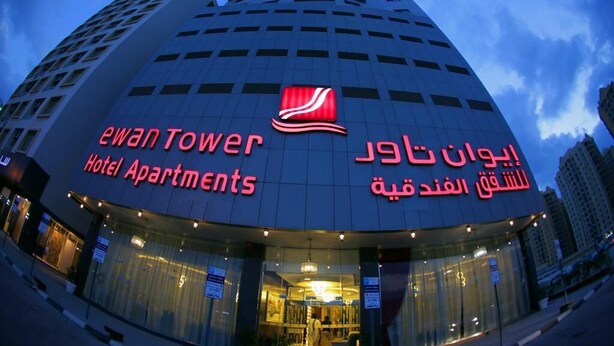 Un edificio de hotel con un letrero llamativo que dice 'Ewan Tower Hotel Apartments'.