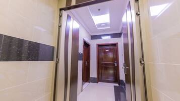 A hallway with a tiled floor, a wooden door, and a ceiling light.