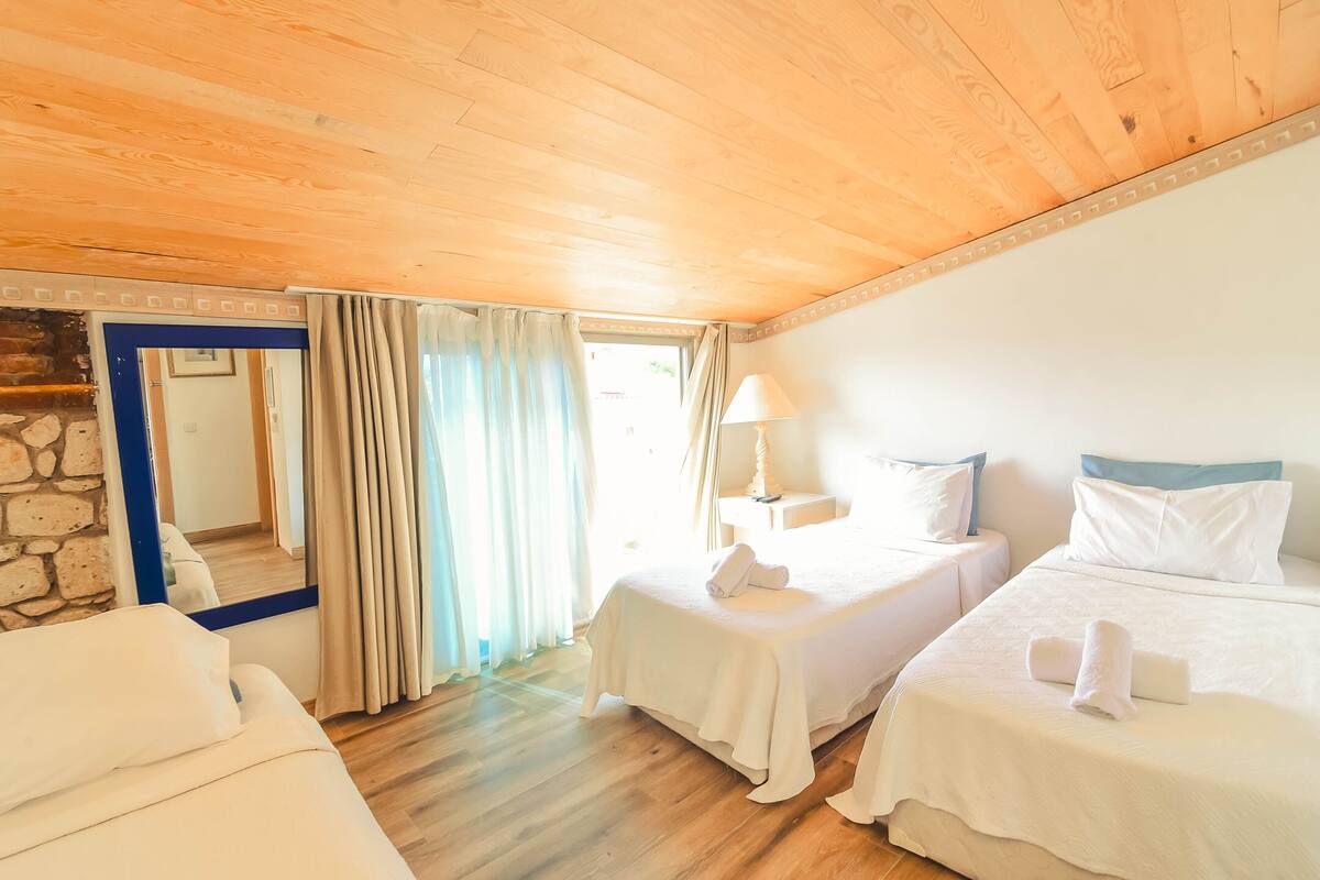 A room with two beds, a mirror, a lamp, and a stone wall.