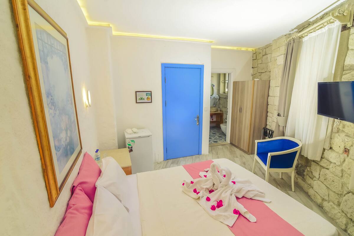 A hotel room with a bed, a chair, a television, and a bathroom visible through an open door.