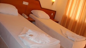 Una habitación de hotel con dos camas individuales, cada una con una almohada y una mesita de noche.