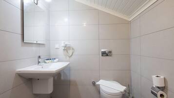 Un baño con lavamanos, inodoro y espejo blancos.