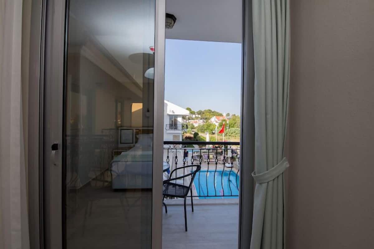 A balcony with a pool, a chair, and a table.