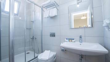 Un baño moderno con cabina de ducha de vidrio, un lavamanos blanco y un inodoro.