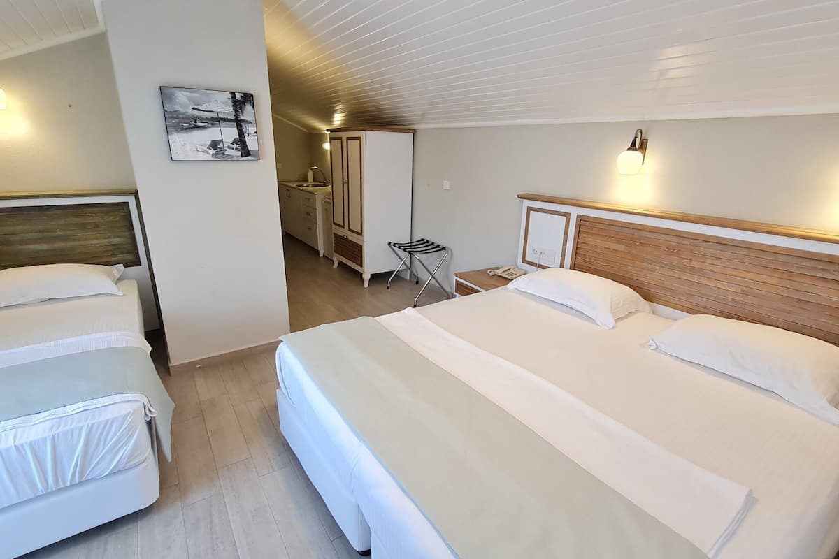 A hotel room with two beds, a wooden headboard, a small desk, and a chair.