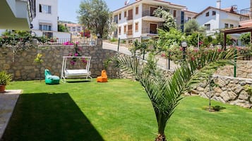 A well-maintained garden with a lawn, a swing, and a palm tree.