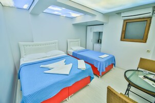 Habitación de hotel con dos camas, una mesita y una ventana.