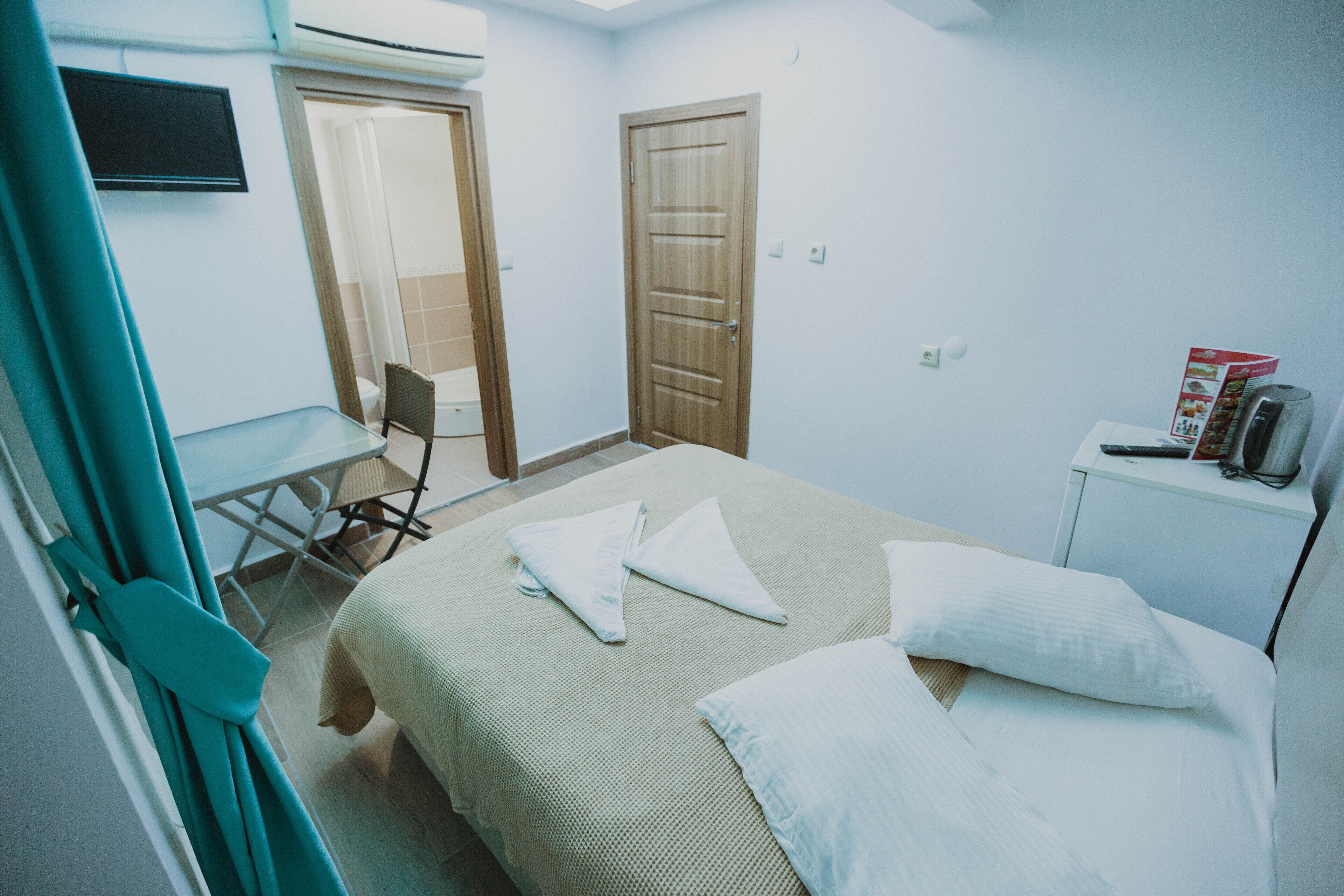 Una habitación de hotel con cama, sillón, escritorio y televisión.