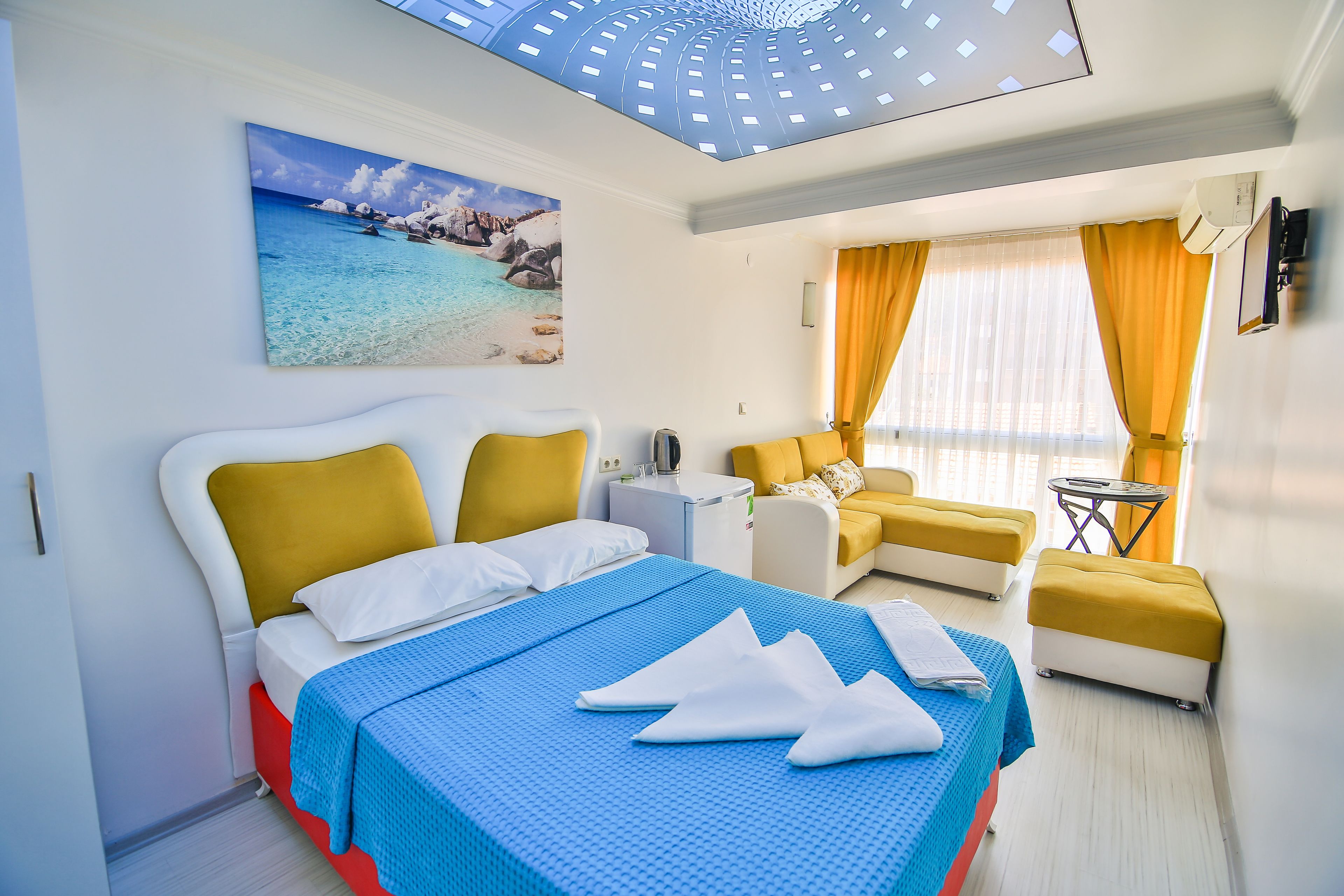 Una habitación de hotel con una cama, un sofá, una mesita y una ventana con cortinas.