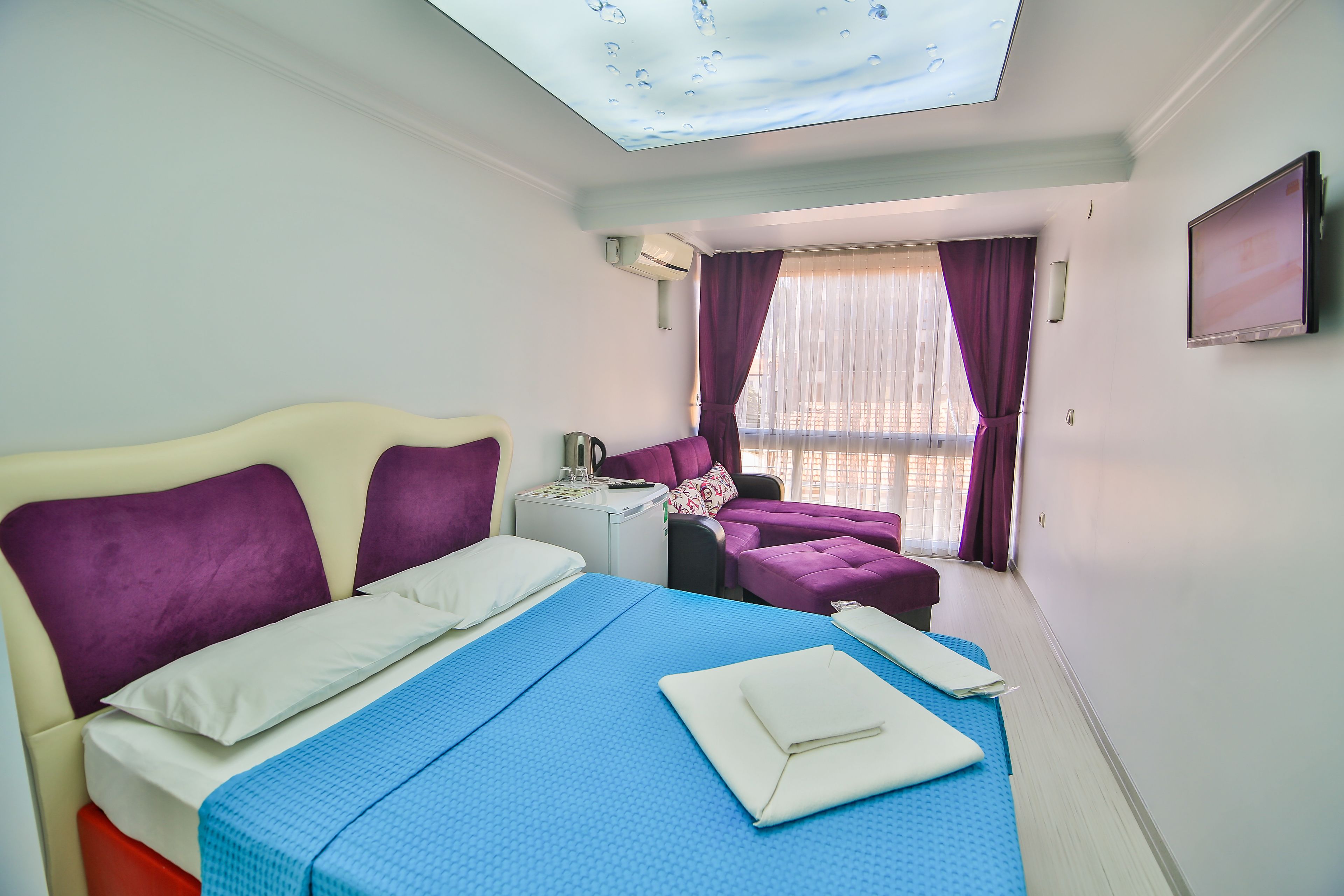 Habitación de hotel con cama, escritorio, silla y televisión.