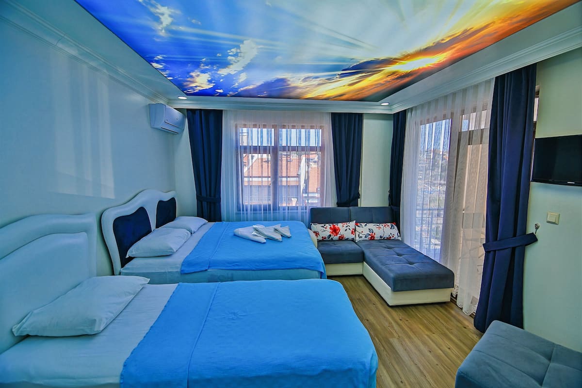 Une chambre d’hôtel avec deux lits, un canapé et une fresque murale au plafond.