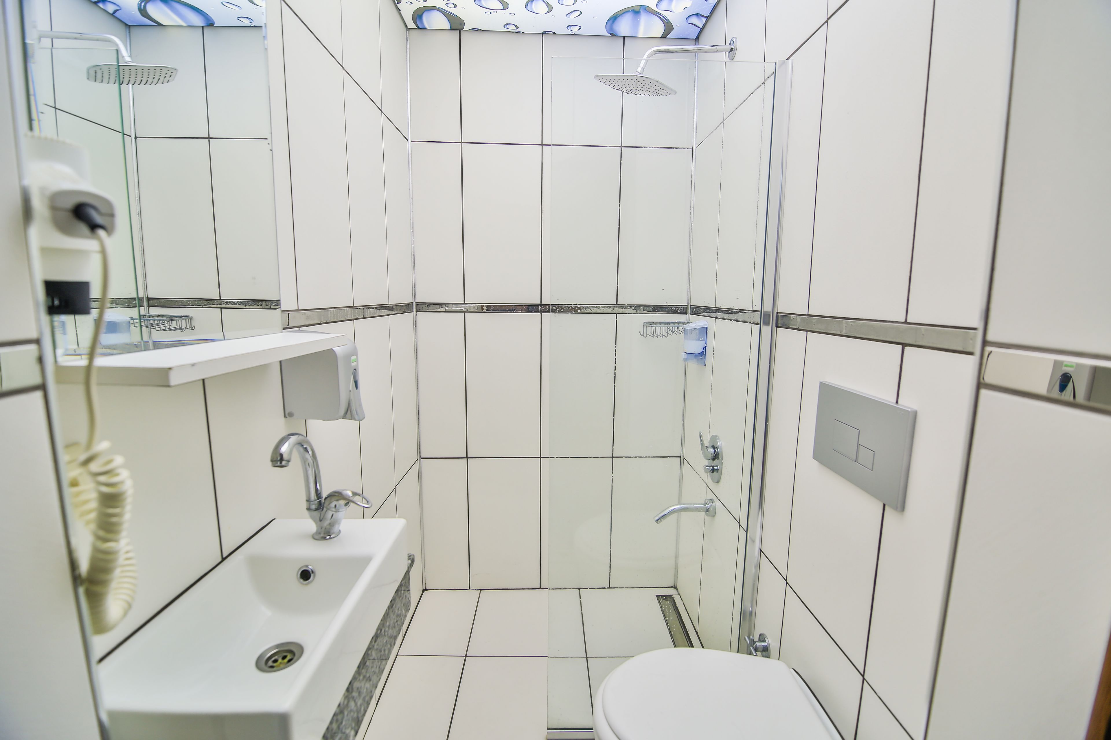 Un baño pequeño y moderno con lavamanos, inodoro y ducha.