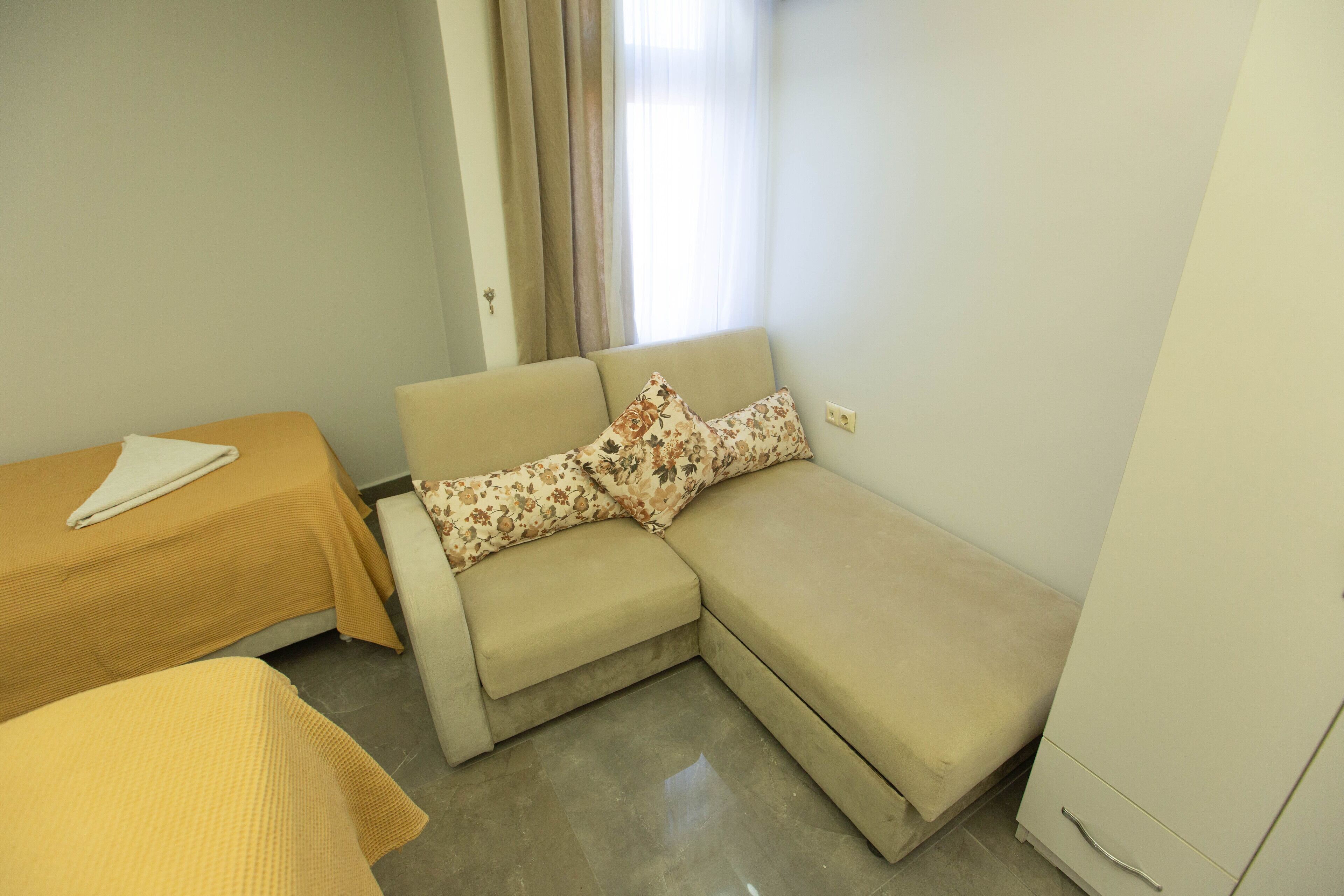 A small, clean room with a sofa, a small table, and a cabinet.