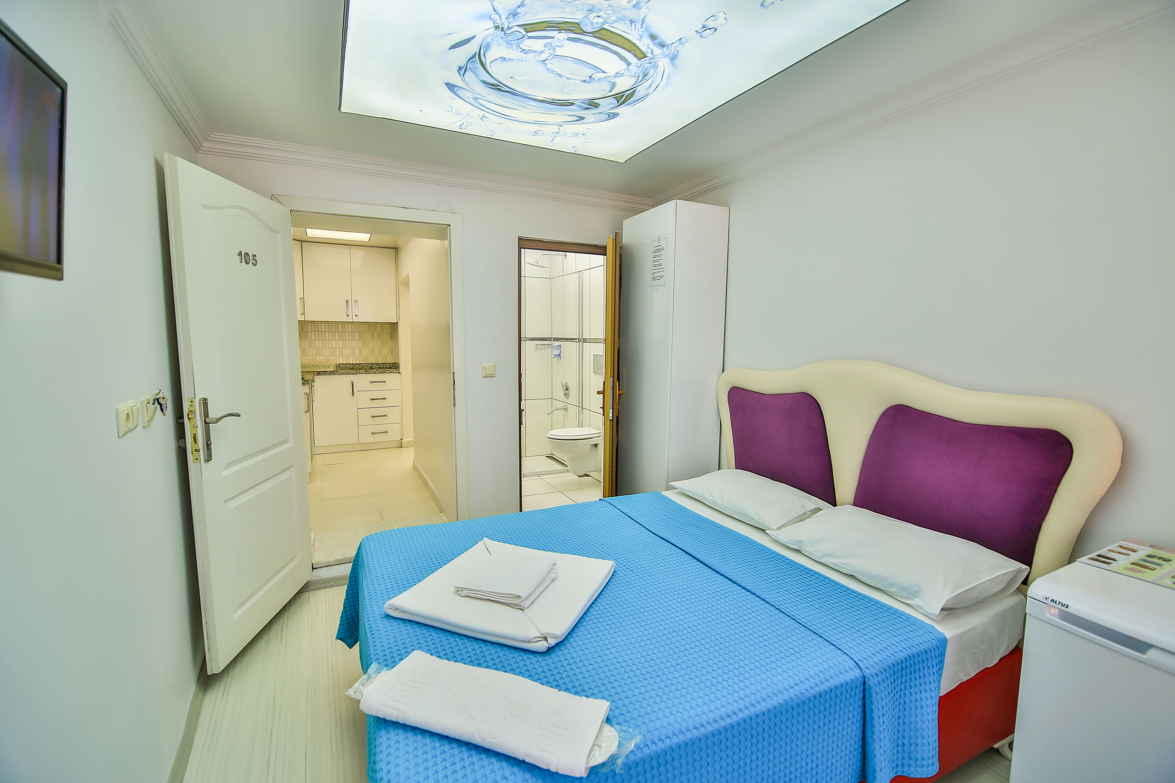 A hotel room with a bed, a bathroom, and a kitchenette.