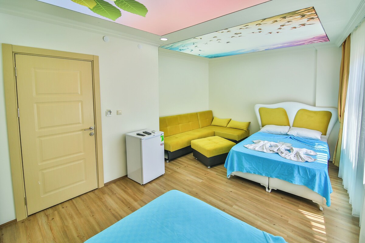 Een kamer met een bed, een bank, een klein tafeltje en een muurschildering aan het plafond.