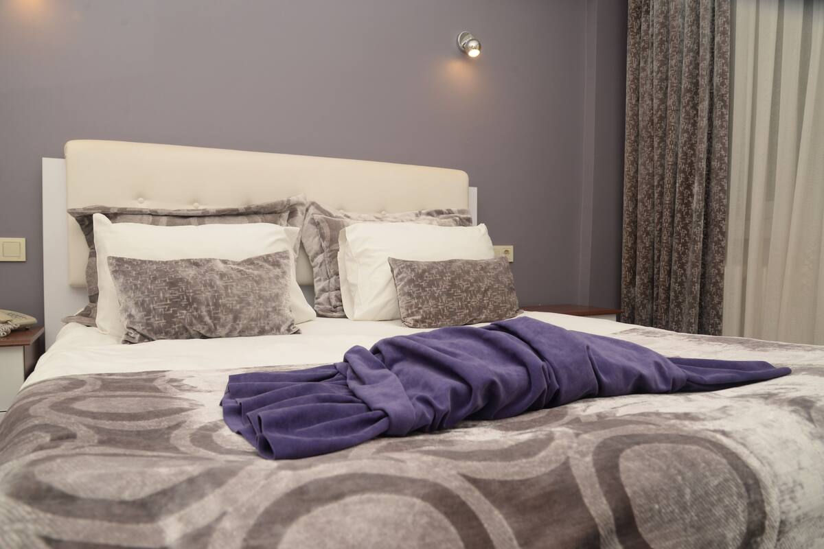 A neatly made bed with a patterned bedspread, a headboard, and two bedside lamps.