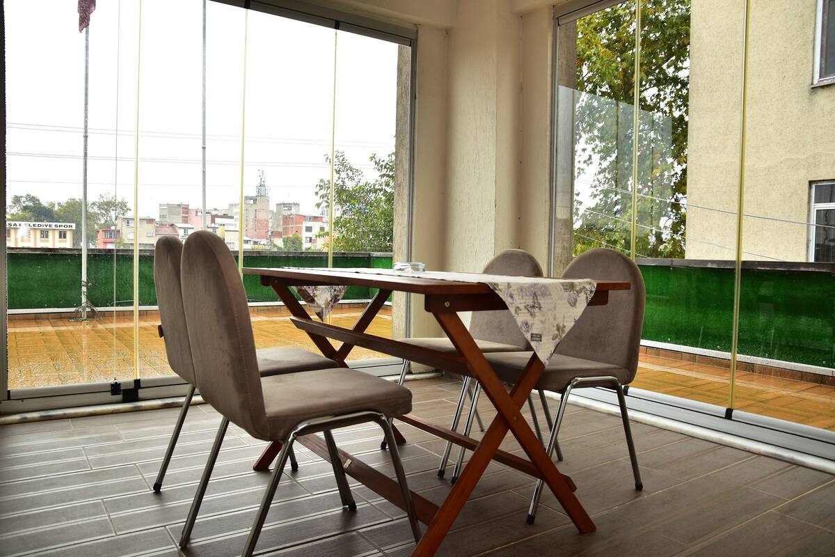 A dining area with a table and chairs, large windows, and a view of the cityscape.