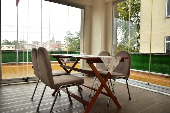 A dining area with a table and chairs, large windows, and a view of the cityscape.