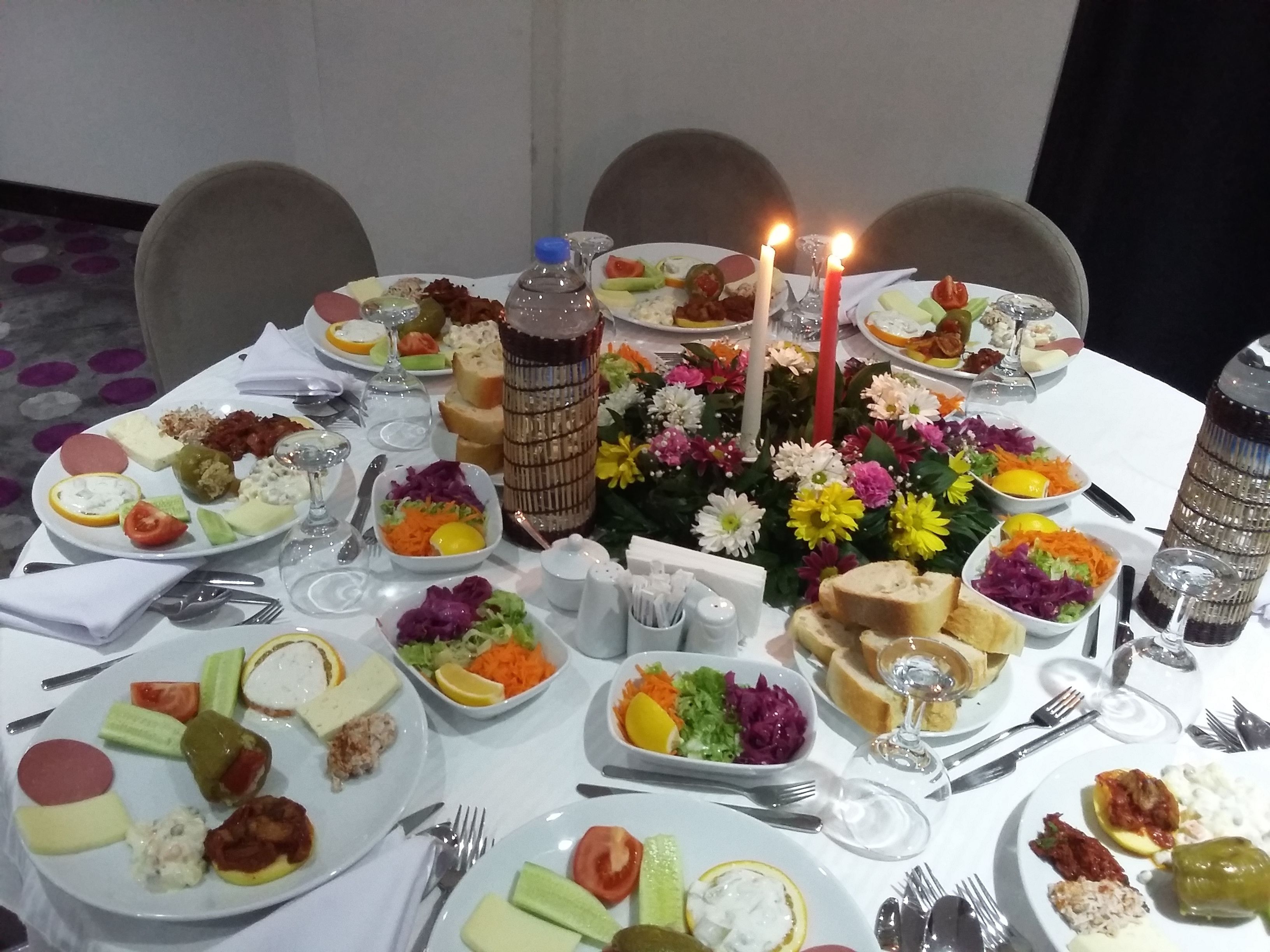 Una mesa de comedor preparada con diversos platos, velas y un centro de mesa decorativo.