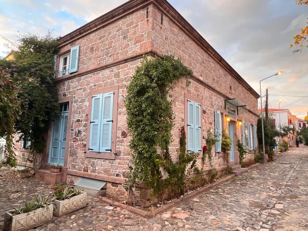 Un bâtiment en pierre avec des volets bleus, une rue pavée et un ciel dégagé.