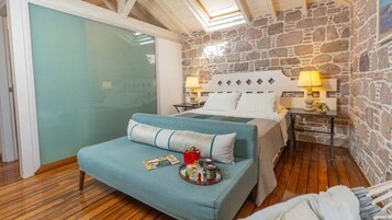 Un dormitorio con cama, un banco con bandeja y una pared de piedra.