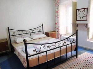 A single bed with a metal frame and floral bedding in a room with a blue carpet and a patterned rug.