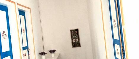 A room with a white ceiling, a white wall with a small framed picture, and a white door with blue trim.