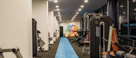 A gym with exercise equipment, a blue running track, and large windows.