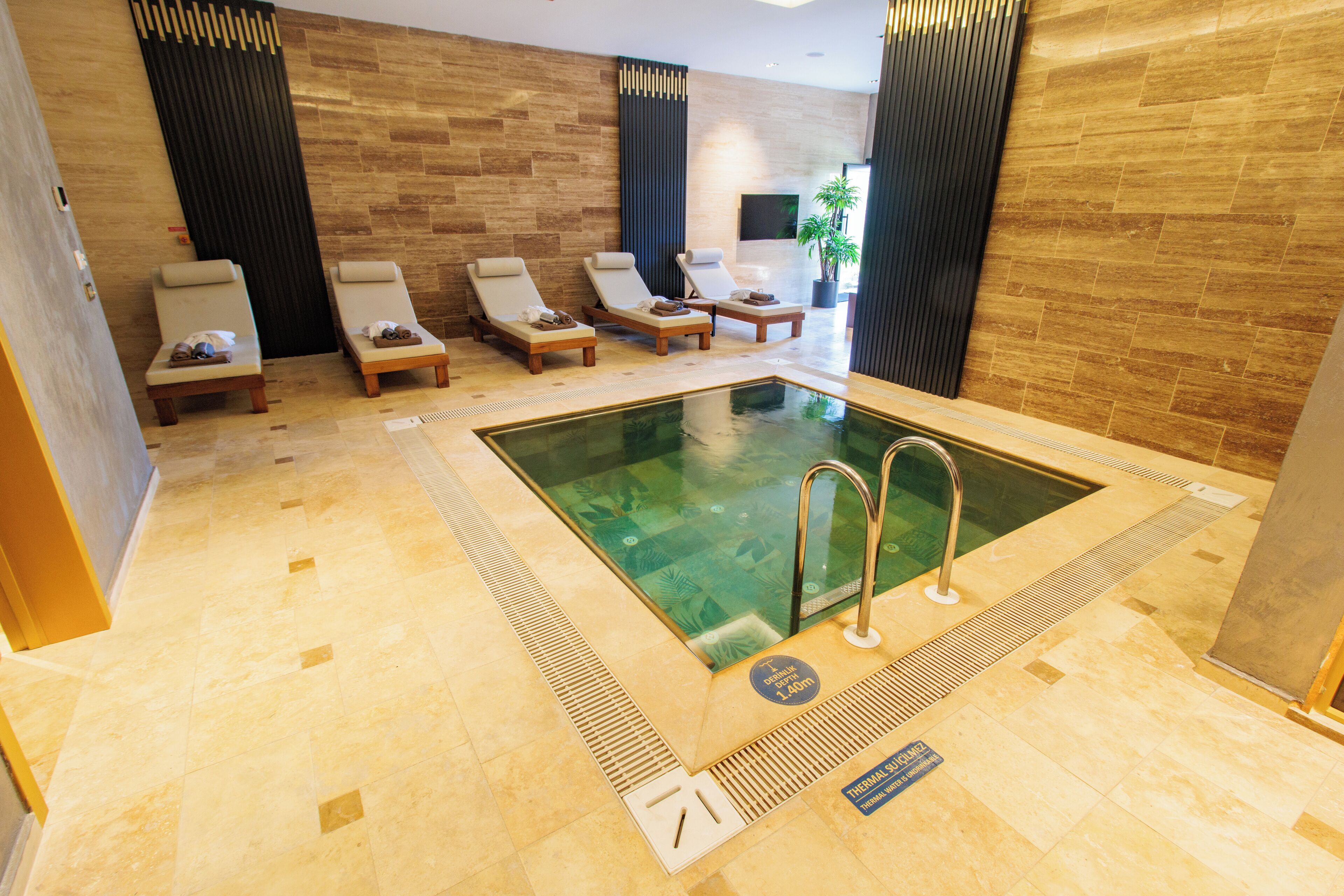 Un espace piscine intérieur moderne, doté de chaises longues et d’une eau cristalline.