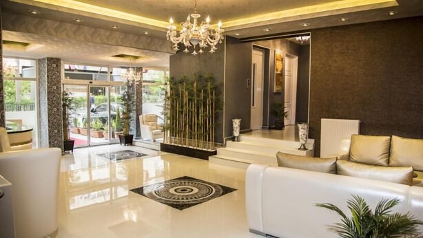 Um hall de hotel moderno com um sofá branco, um candelabro e um balcão de recepção.