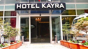A entrada do Hotel Kayra, com design moderno, com portas de vidro e plantas em vasos.