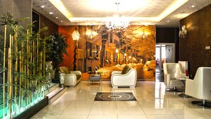Um hall de entrada com design moderno, com balcão de recepção, área de estar e plantas decorativas.