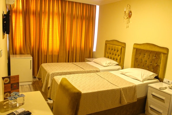 Une chambre d’hôtel avec deux lits, un petit bureau, un téléphone et un téléviseur fixé au mur.