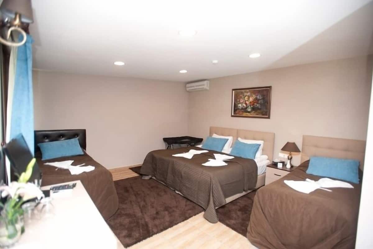 Habitación de hotel con tres camas, un escritorio y una silla.