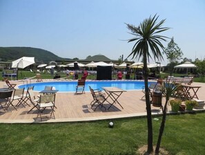 A pool area with lounge chairs and umbrellas, surrounded by a wooden deck and grass. - Riva's Club (Çekmeköy)